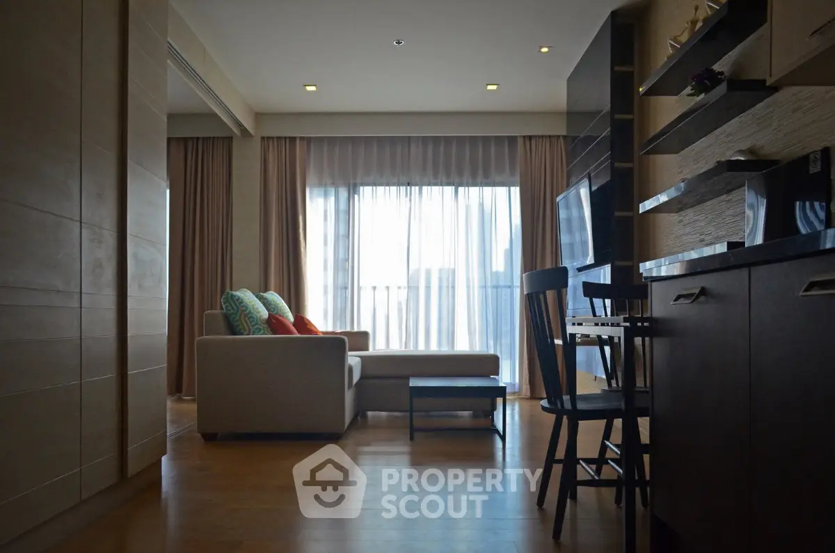 Modern living room with cozy sofa and open kitchen layout, featuring large windows and stylish decor.