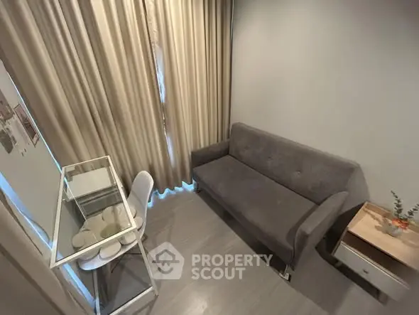 Cozy small living room with gray sofa and glass-top table, ideal for compact spaces.