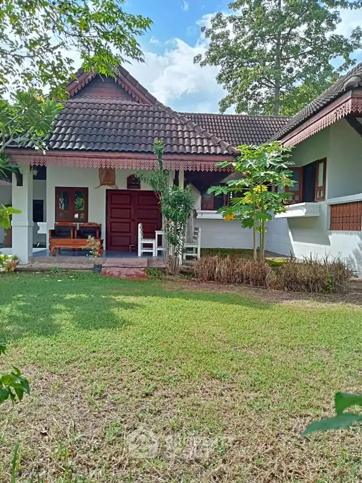 Charming traditional-style house with lush garden and inviting front porch, perfect for serene living.