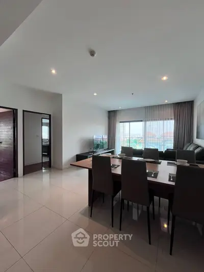 Spacious modern living room with dining area and large windows offering a scenic view.