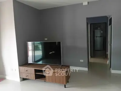 Modern living room with sleek TV stand and large flat-screen TV, showcasing minimalist interior design.