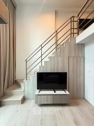 Modern loft apartment with stylish staircase and sleek TV setup, perfect for urban living.