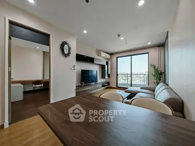 Modern living room with large window and city view, featuring stylish furniture and open layout.