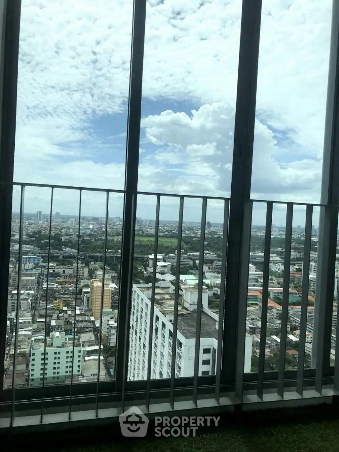 Stunning high-rise city view from a balcony with expansive skyline and clouds.