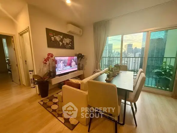 Modern living room with city view, stylish decor, and cozy dining area in a high-rise apartment.