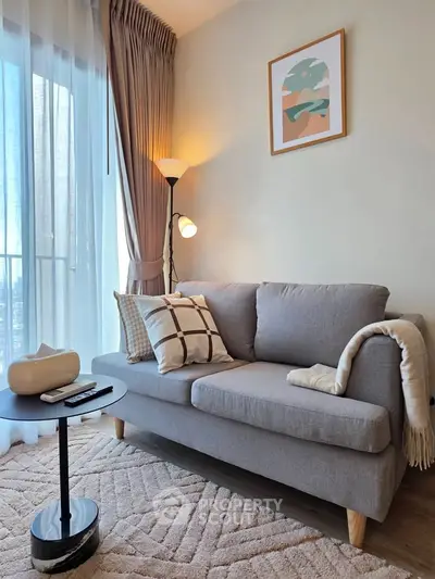 Stylish living room with modern decor, cozy sofa, and natural light from large window.