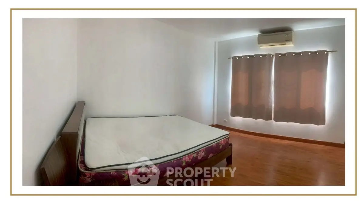 Spacious bedroom with wooden flooring and air conditioning, perfect for comfort and relaxation.