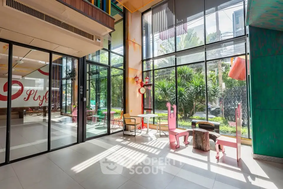 Modern building entrance with stylish seating and large glass windows offering garden views.