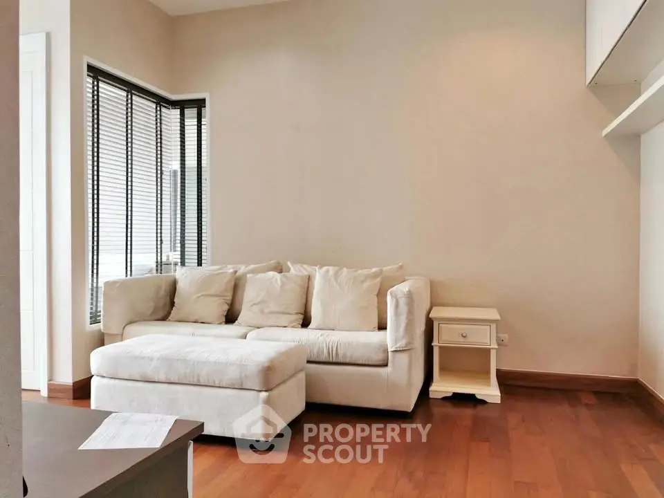 Cozy living room with plush white sofa and wooden flooring, perfect for relaxation.