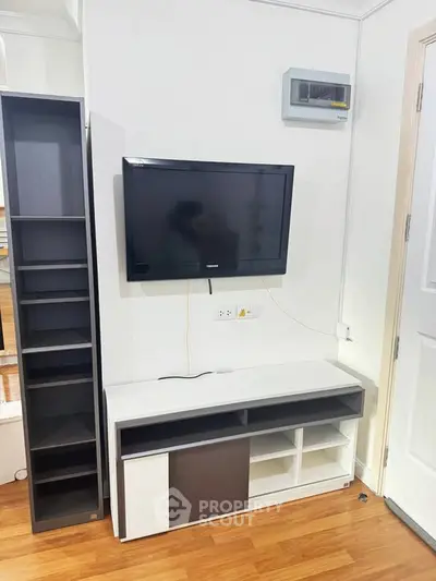 Modern living room with wall-mounted TV and sleek storage unit on wooden flooring.