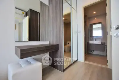 Modern interior with mirrored closet and bathroom view, featuring sleek wood finishes.