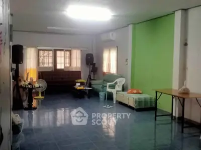 Spacious living room with blue tiled floor and green accent wall, featuring cozy seating and natural light.