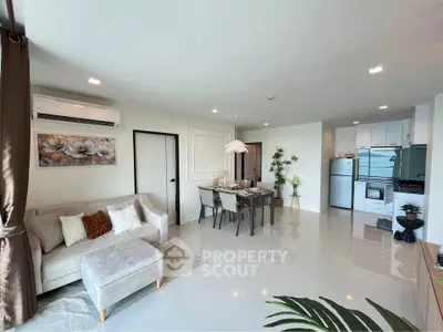 Modern open-plan living room with dining area and kitchen, featuring sleek furniture and bright lighting.