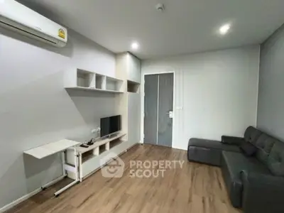 Modern living room with sleek furniture and wooden flooring, featuring a wall-mounted TV and air conditioning.