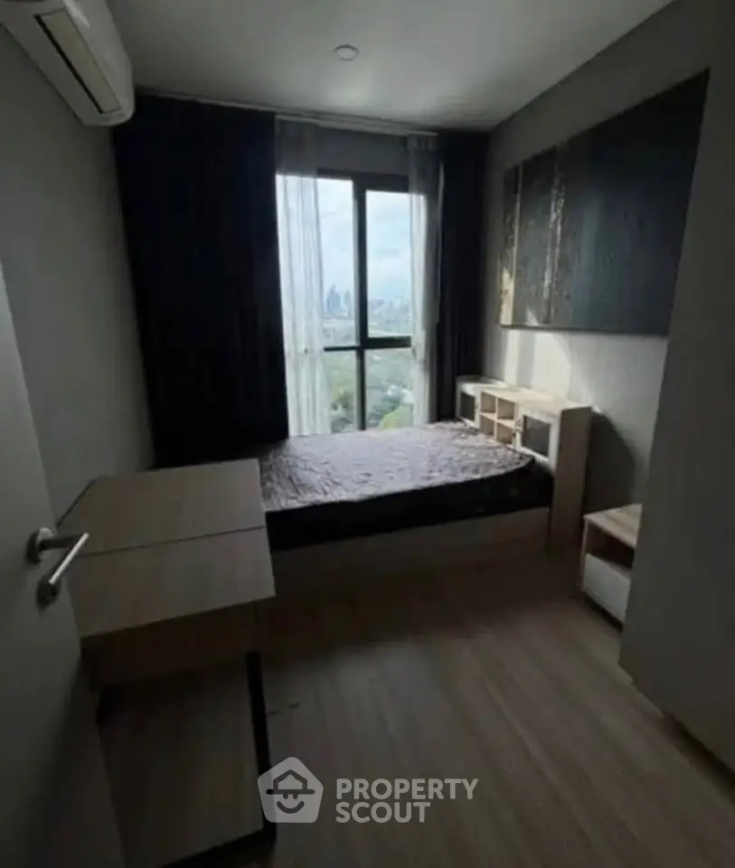 Cozy bedroom with modern furnishings and city view, perfect for urban living.