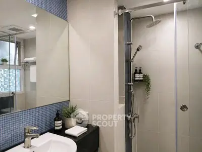 Modern bathroom with sleek shower and stylish sink area, featuring elegant fixtures and contemporary design.