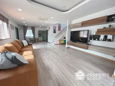 Spacious living room with modern design, elegant wooden flooring, and ample natural light, featuring a large comfortable sofa and a sleek entertainment unit.