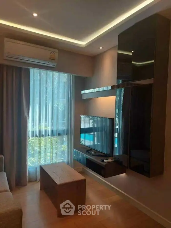 Modern living room with sleek TV setup and natural light through large window.
