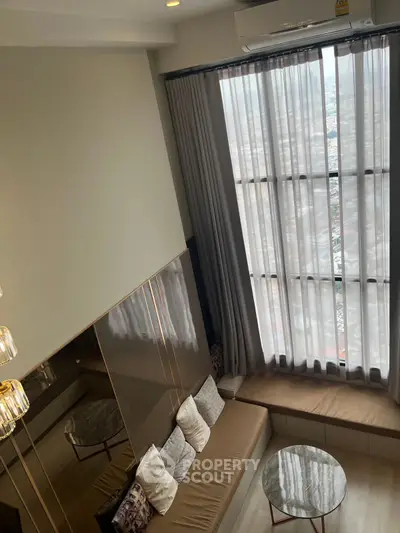 Modern living room with large windows and elegant decor in high-rise apartment.
