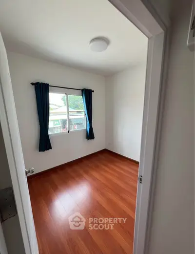 Bright bedroom with wooden flooring and large window, perfect for natural light.