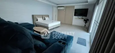 Spacious modern bedroom with plush seating and wall-mounted TV