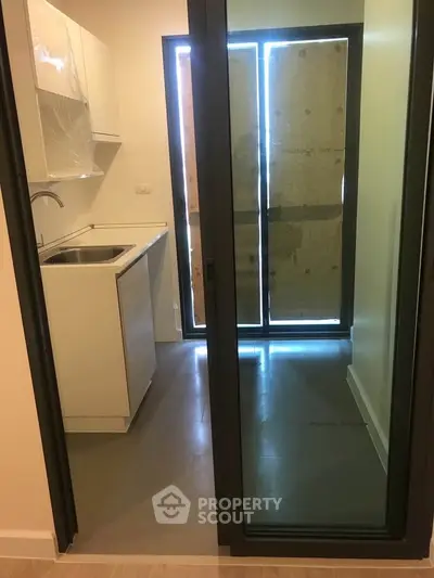 Compact kitchen with sliding glass door and modern cabinetry in a cozy apartment.