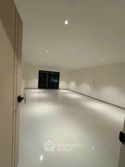 Spacious empty room with glossy tiled floor and recessed lighting, ideal for customization.