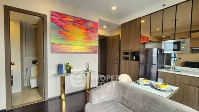Modern open-layout living room with kitchen, featuring vibrant wall art and sleek appliances.