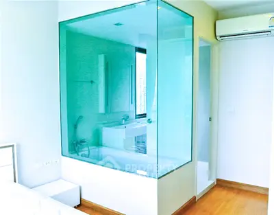 Modern bedroom with glass-enclosed bathroom and air conditioning unit.