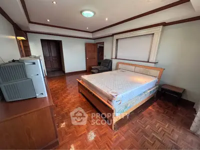 Spacious bedroom with wooden flooring and modern furnishings in a luxurious home.