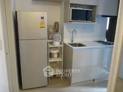 Compact modern kitchen with stainless steel fridge and microwave, ideal for urban living.