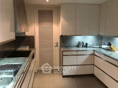 Modern kitchen with sleek cabinetry and granite countertops, featuring stainless steel sink and appliances.