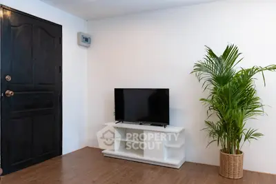 Modern living room with TV stand and potted plant, featuring sleek wooden flooring.