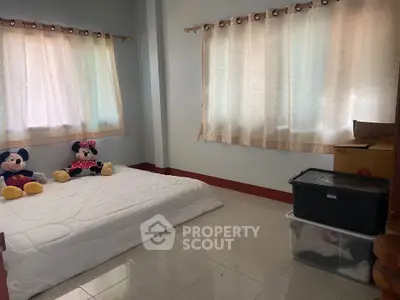 Cozy bedroom with natural light and simple decor, featuring a mattress on the floor and charming curtains.