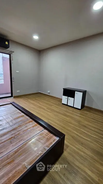 Spacious unfurnished bedroom with wooden flooring and natural light