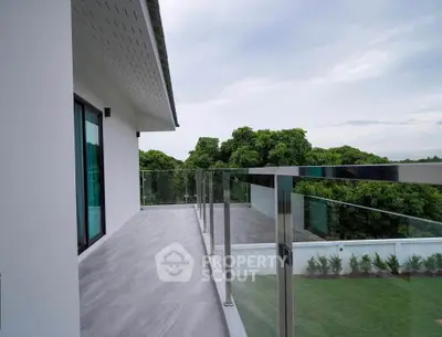 Spacious balcony with glass railing and scenic greenery view