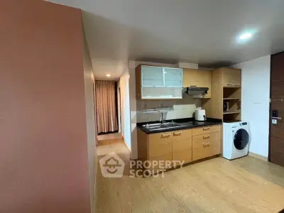Modern kitchen with wooden cabinets and washing machine in open layout apartment.