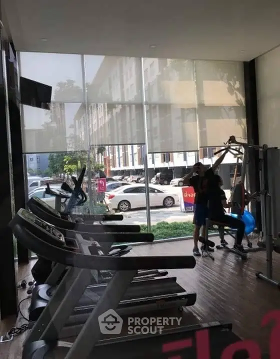 Modern gym with exercise equipment and large windows in a residential building.