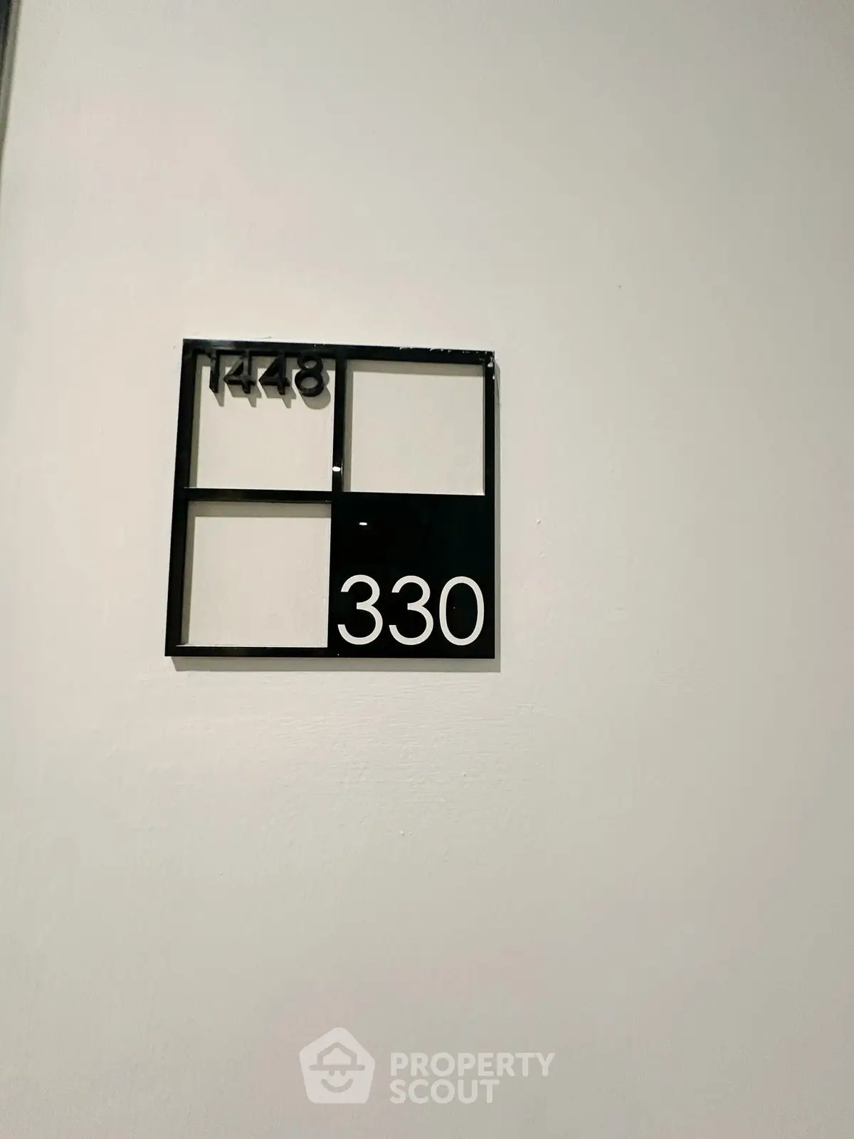Modern apartment number sign on a white wall, showcasing sleek design.