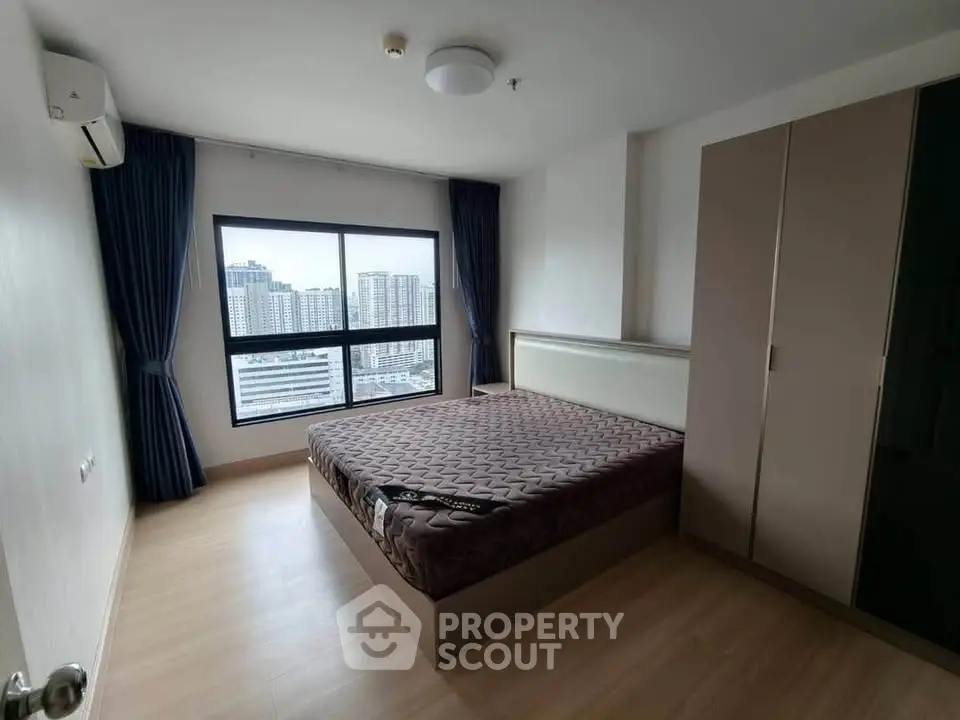 Spacious bedroom with large window offering stunning city views in modern apartment.