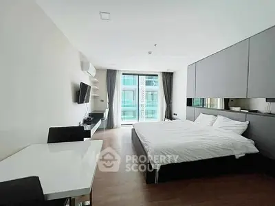 Spacious modern bedroom with large windows and sleek furnishings in a contemporary apartment.