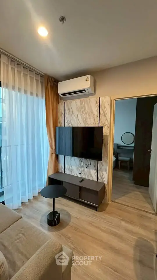 Modern living room with stylish decor and wall-mounted TV, featuring elegant curtains and sleek flooring.