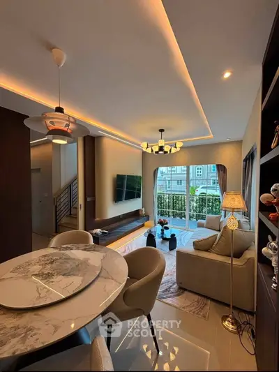 Modern living room with elegant lighting and stylish furniture, featuring a cozy seating area and a view of the balcony.