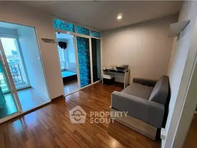 Modern living room with wooden flooring and balcony access in urban apartment