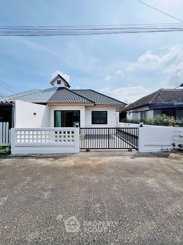 Charming single-story house with tiled roof and gated entrance in a serene neighborhood.