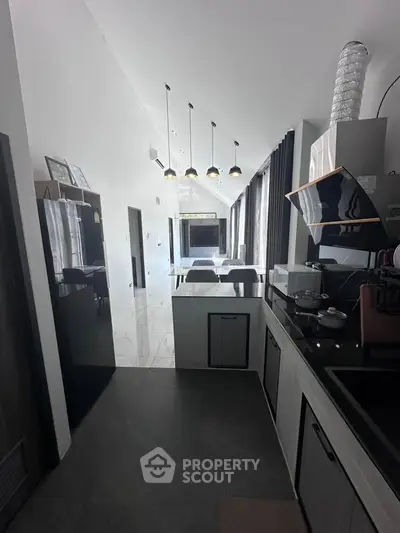 Modern kitchen with sleek design and open layout, featuring high ceilings and stylish lighting.