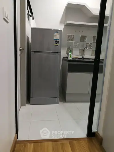 Modern kitchen with sleek fridge and stylish backsplash in compact layout.