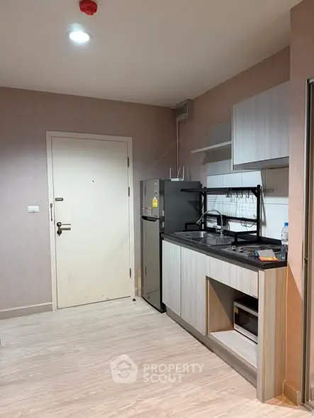 Modern compact kitchen with sleek cabinetry and appliances in a cozy apartment.