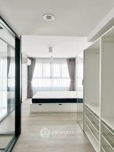 Spacious modern bedroom with large windows and built-in storage, offering ample natural light and sleek design.