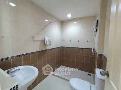 Modern bathroom with sleek tiles and shower area in a contemporary home.